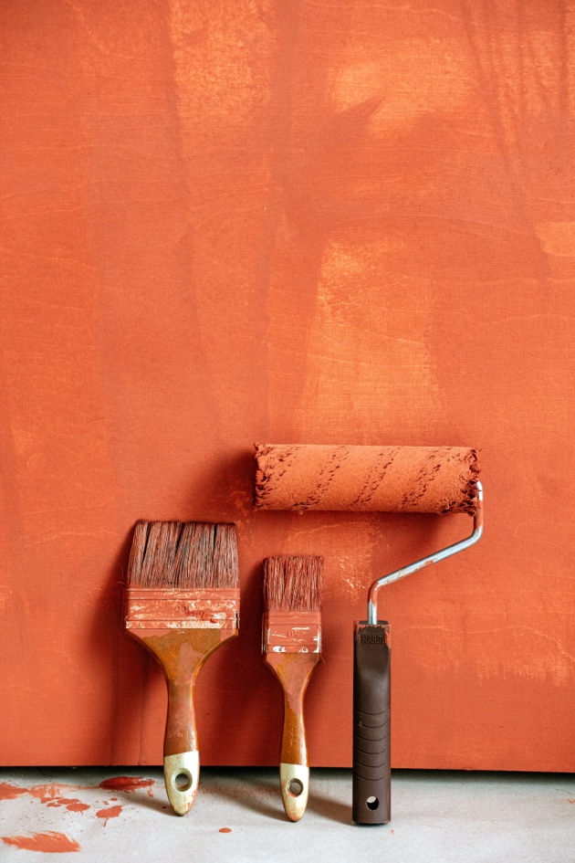 Paint brushes with a bold color on the wall behind