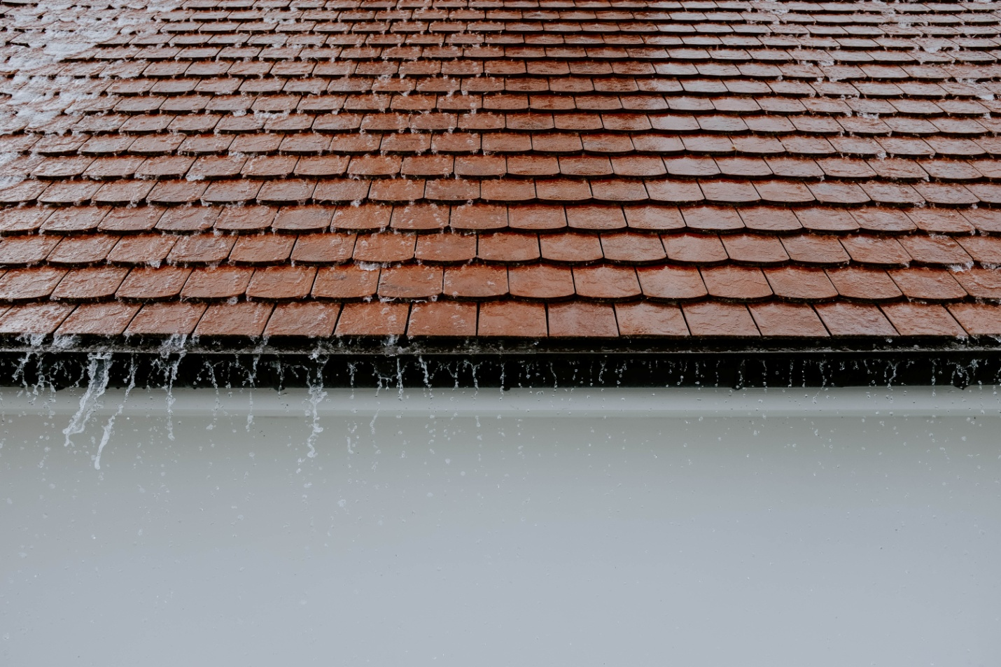 A close-up of a tile roof while raining