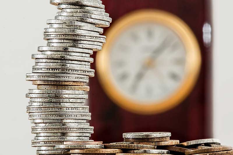 Stacked coins next to a clock